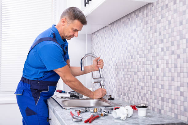 Plumber repairing a kitchen faucet and sink plumbing