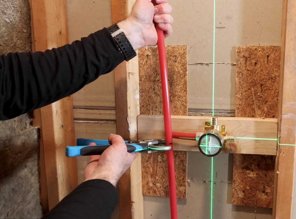 Plumber measuring and cutting PEX pipe for installation