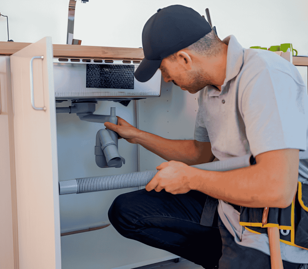 Professional plumber inspecting and repairing a kitchen sink drain and plumbing system.