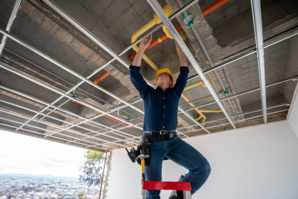 Plumber installing overhead pipes in a commercial building