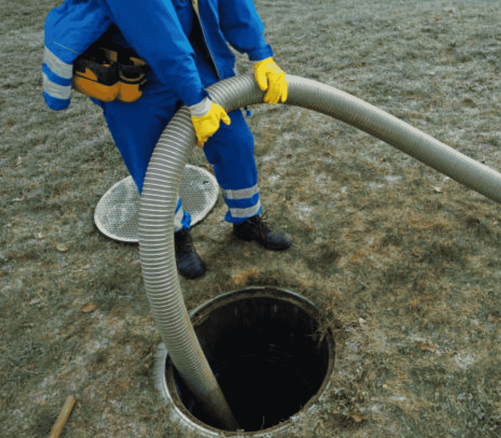 Technician pumping and cleaning a residential septic tank with vacuum equipment.