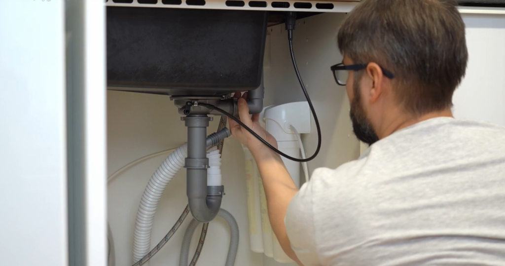 Plumber inspecting pipes under sink