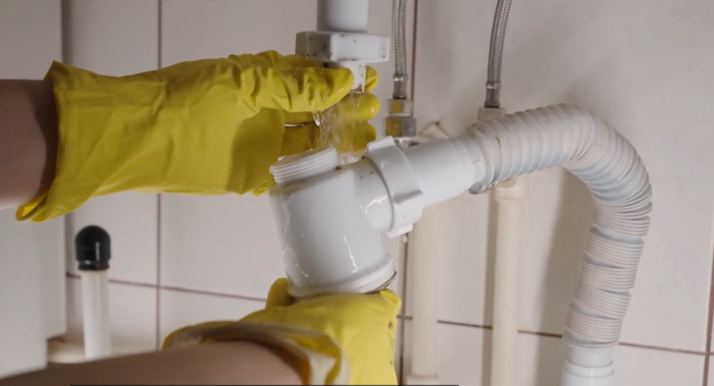 Plumber repairing leaking P-trap pipe
